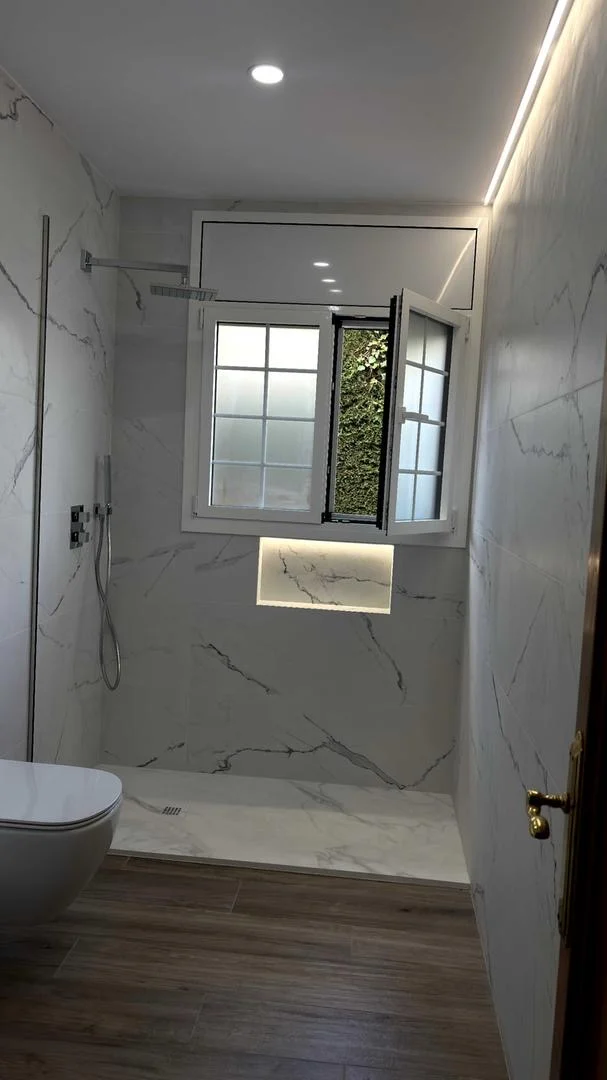 Baño con paredes de mármol, ducha a ras de suelo con iluminación LED y suelo de madera