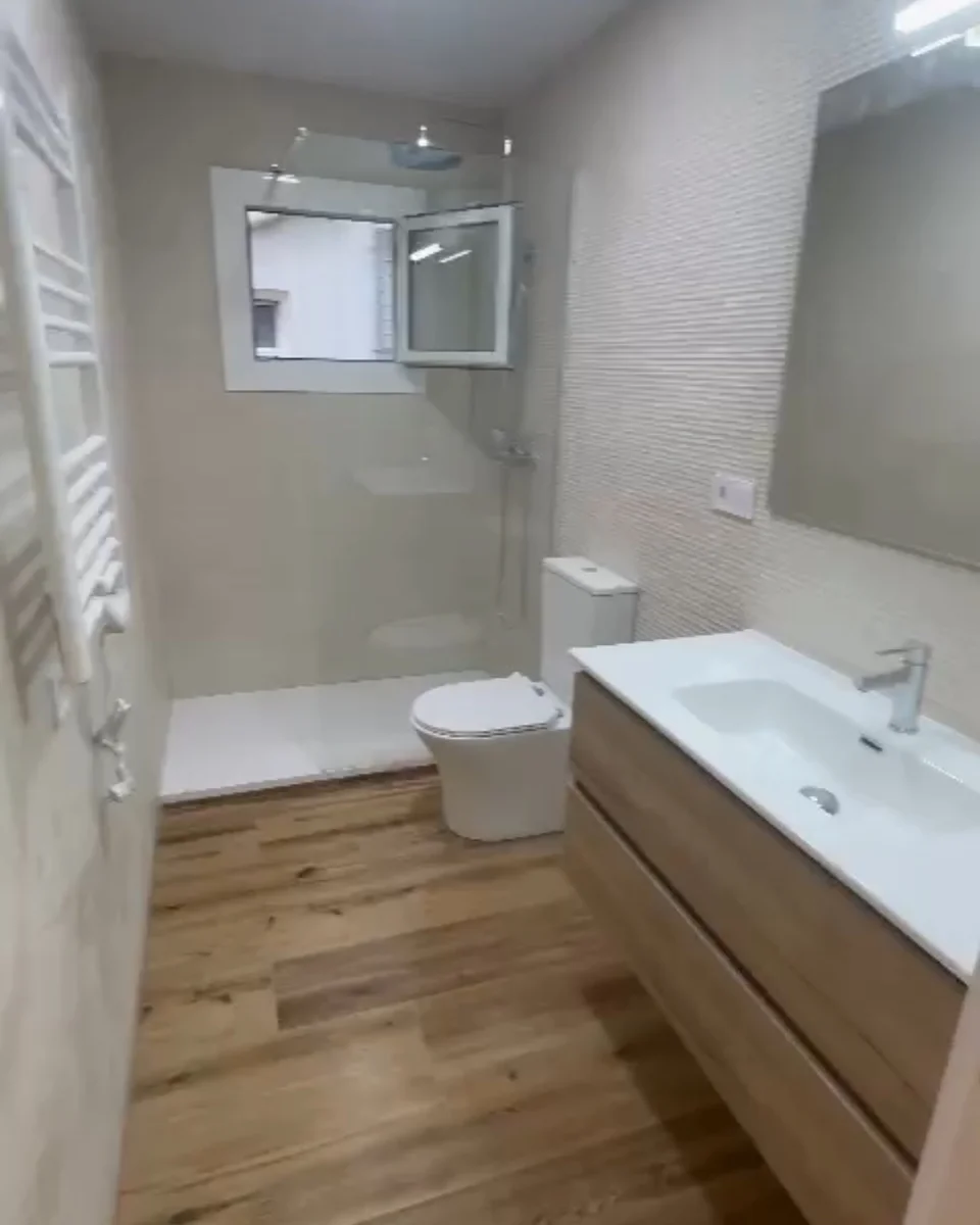 Baño con suelo de madera, mueble suspendido y azulejo texturizado
