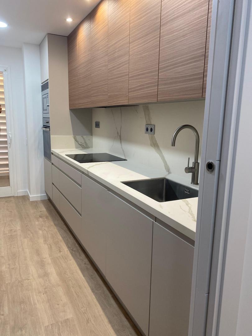Cocina con muebles superiores de madera y encimera de mármol blanco
