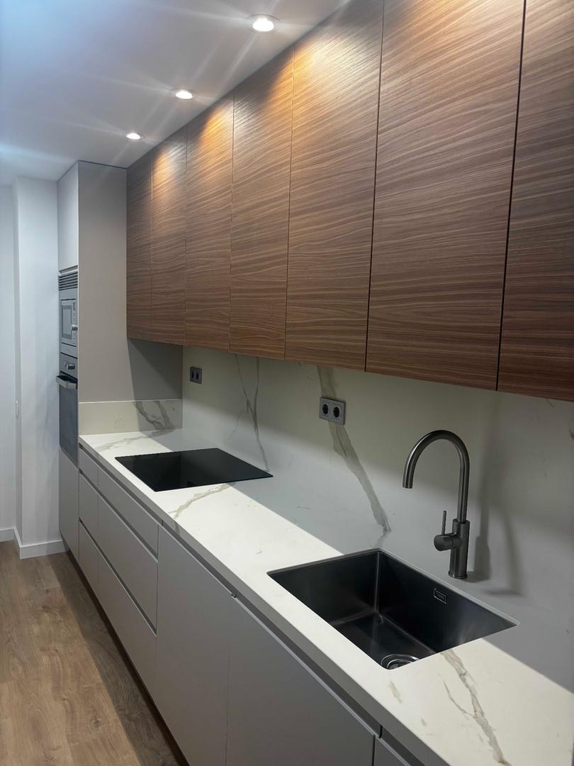 Cocina con muebles superiores de madera y doble fregadero negro integrado
