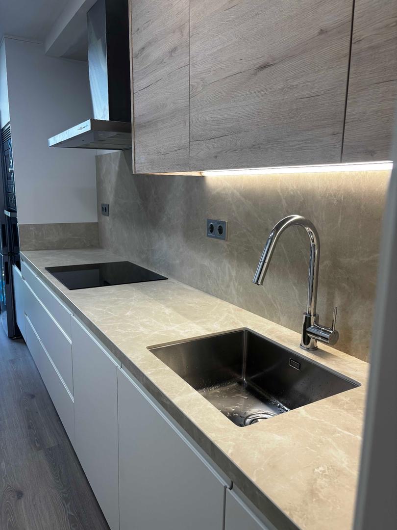 Cocina con encimera de piedra natural, muebles superiores de madera y fregadero integrado