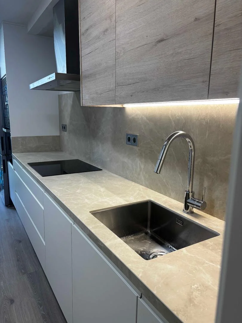 Cocina con encimera de piedra natural, muebles superiores de madera y fregadero integrado