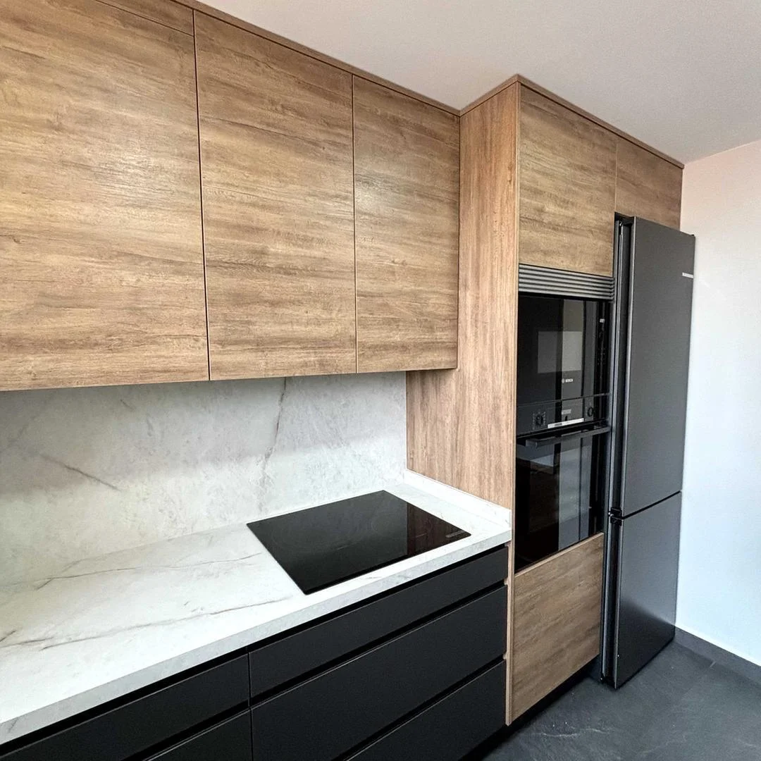 Reforma de cocina en el Vallès con muebles de madera y frente negro mate, electrodomésticos Bosch y encimera de mármol
