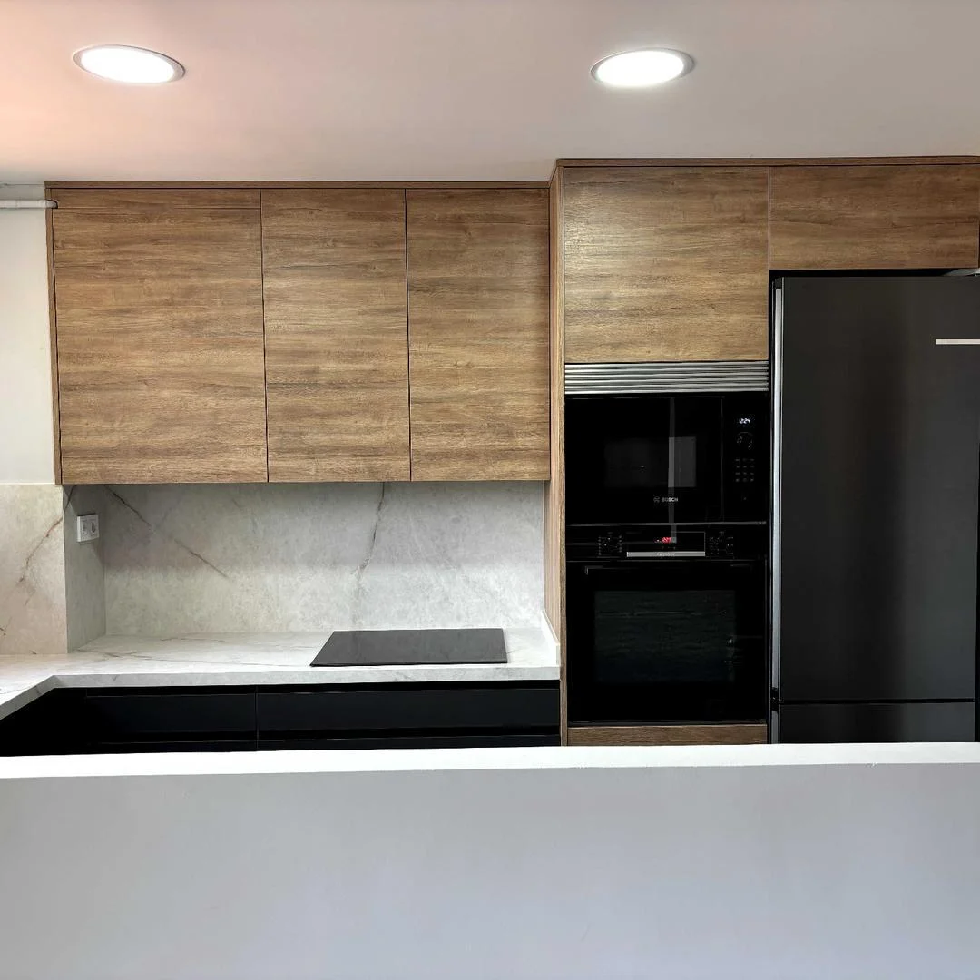 Cocina reformada con columna de horno y microondas Bosch integrados, muebles de madera y frigorífico negro