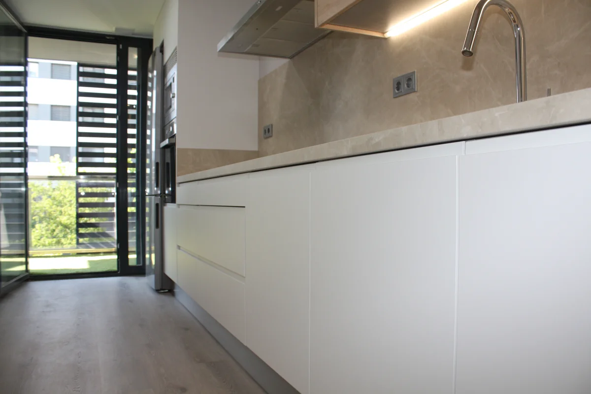 Detalle de cocina moderna sin tiradores con frente porcelánico y encimera de piedra