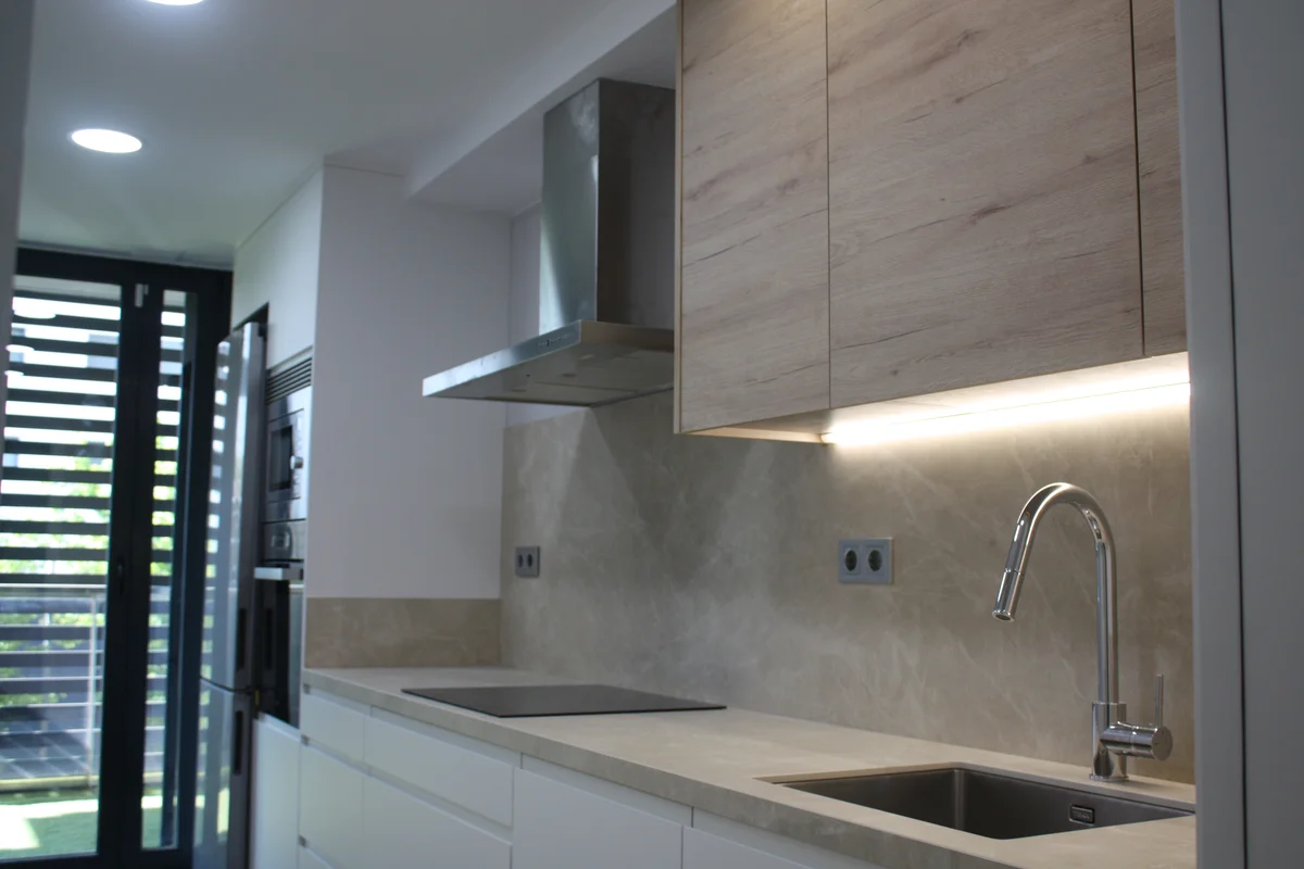 Reforma de cocina en Sabadell con muebles de madera, encimera de piedra y campana de acero inoxidable
