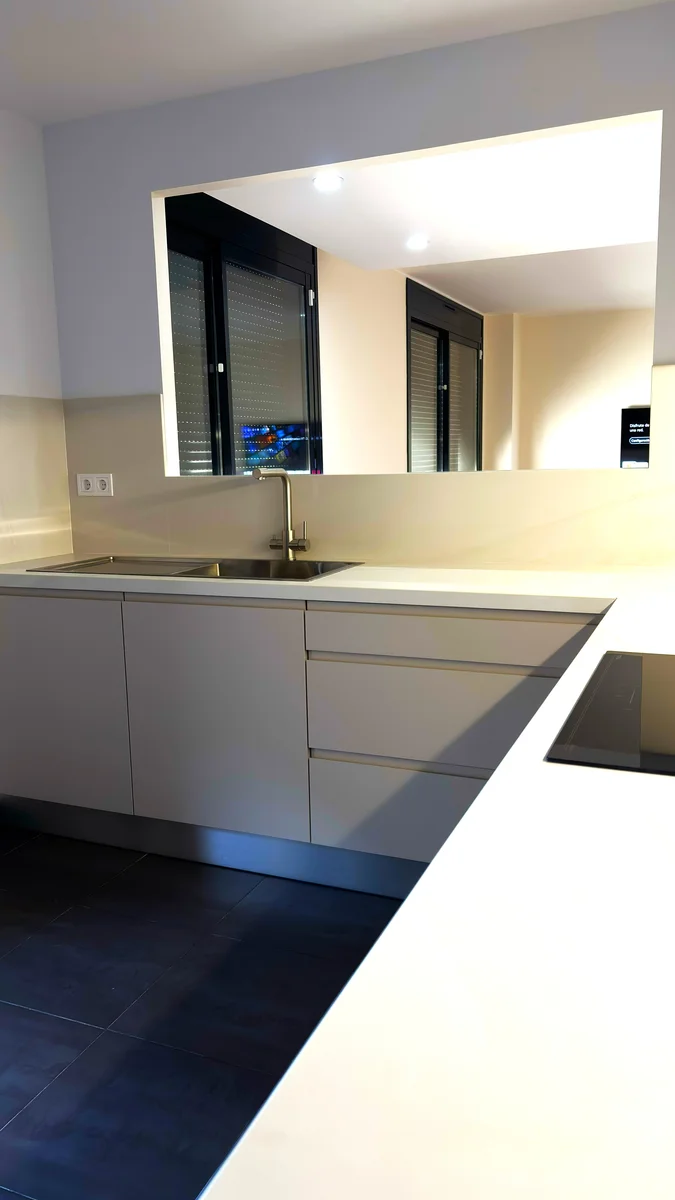 Reforma de cocina abierta al salón con office, encimera blanca y placa de inducción
