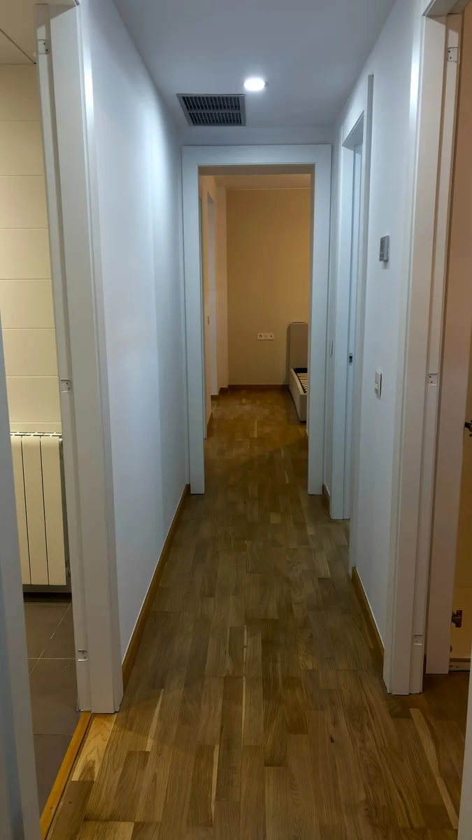Pasillo reformado con suelo de parquet de roble y puertas lacadas en blanco