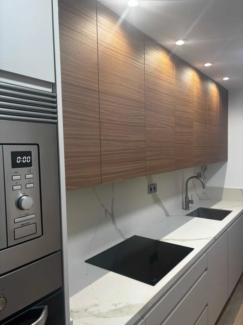 Reforma de cocina con muebles de madera de nogal y encimera de mármol blanco